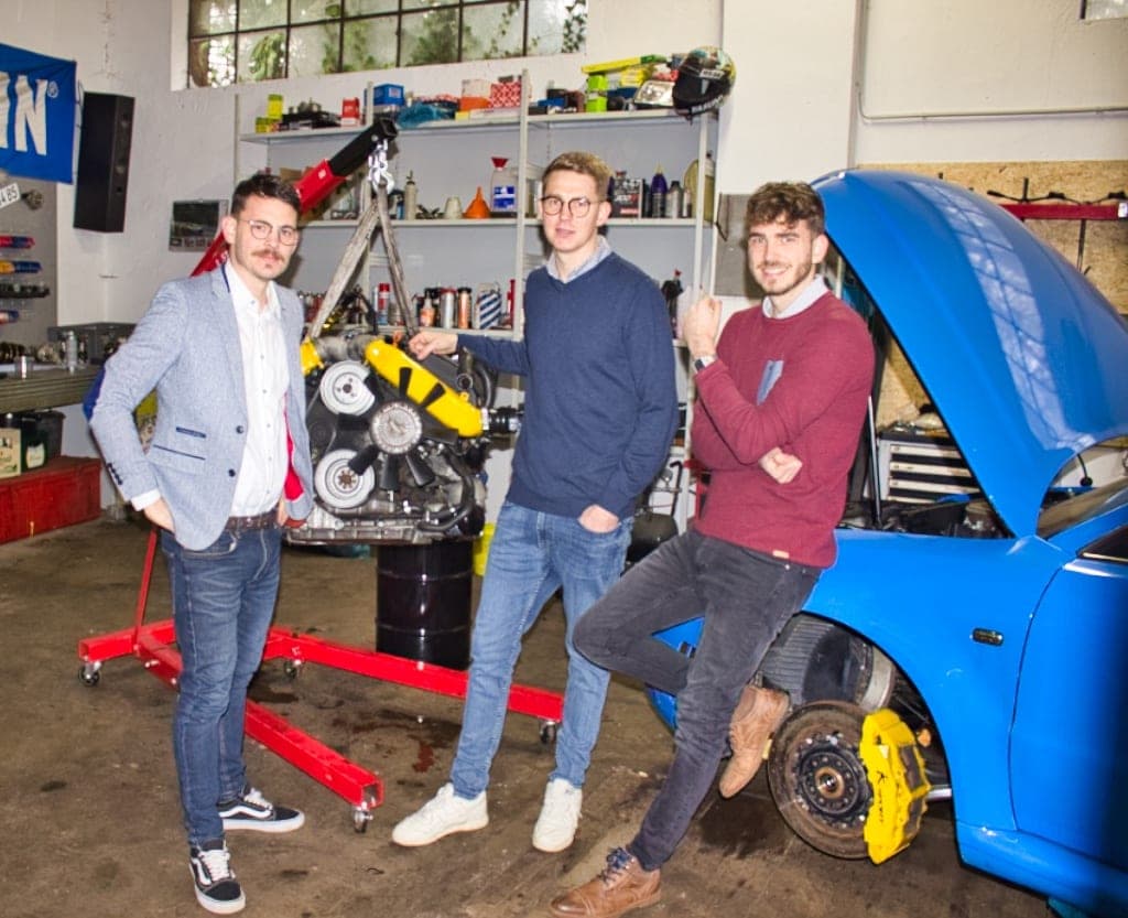Die Schulte-Brüder in der Werkstatt vor einem ausgebauten Motor